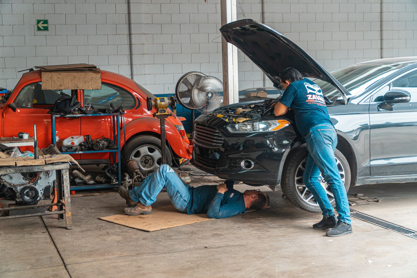 Mechanic working under a lifted car in a clean shop