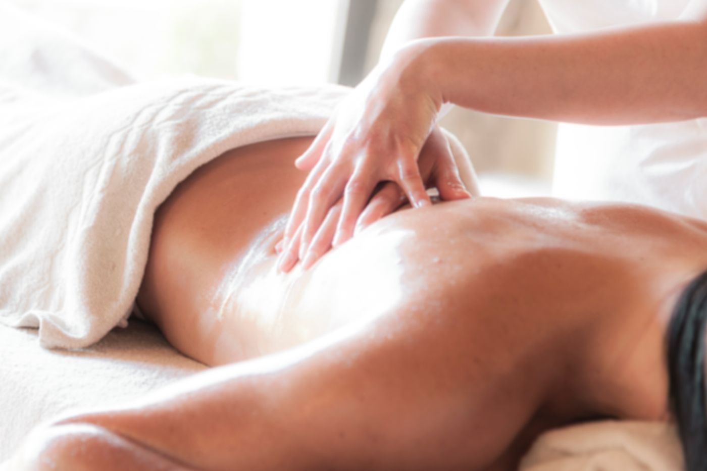 Therapist performing a back massage with warm stones