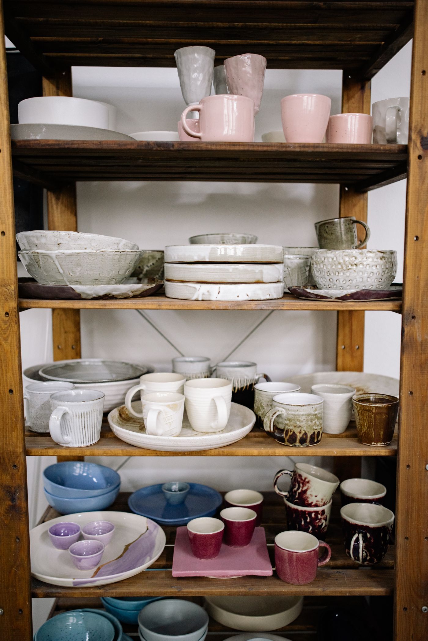 Glazed ceramic cups on wooden shelves