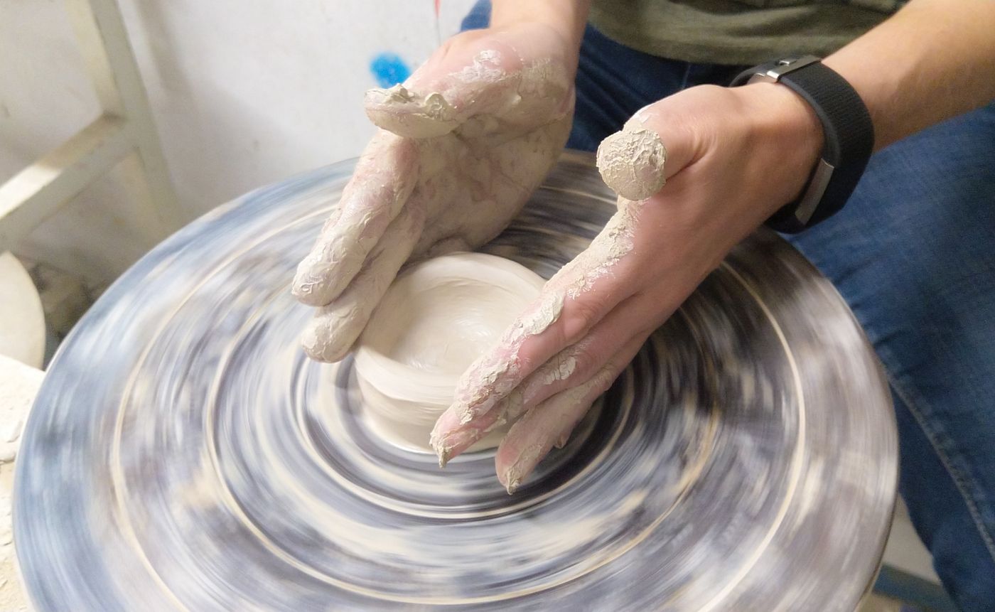 Hands shaping clay on the wheel